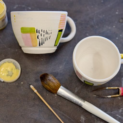 Paintbrushes, underglazes, stoneware clay cup with handle
